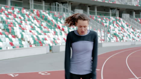 HANDHELD-Portrait-of-Caucasian-female-catching-breath-after-running-on-an-empty-stadium-track-early-in-the-morning.-Shot-with-anamorphic-lens